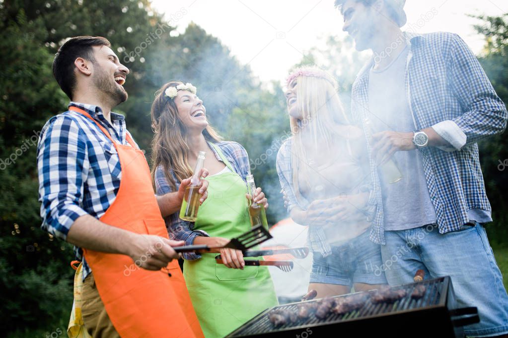 Group of friends having outdoor barbecue laughing together