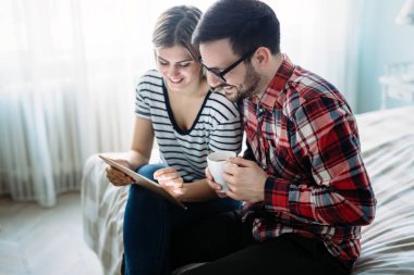 Genç mutlu çift yatak odasında dijital tablet kullanma