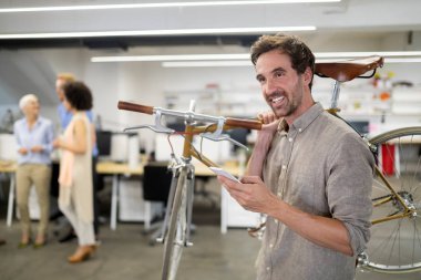 Modern ofiste Bisiklet taşıyan mutlu işadamı