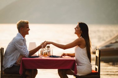 Tropikal tatil akşam yemeği sırasında tost genç romantik çift