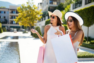 Alışveriş poşetleri tutan alışveriş kadınları tatilde gülerek eğlenerek yürüyor