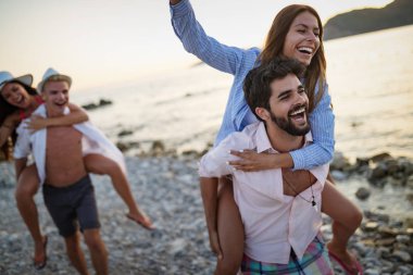 Bir grup mutlu arkadaş tatilde gün batımında sahilde eğleniyorlar.