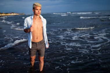 Yakışıklı mutlu adam denizde ya da okyanus arka planda beyaz gömlek giyiyor. Seyahat tatil tatil