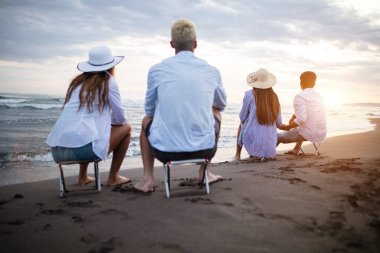 Mutlu arkadaş grubu plajda gün batımında tatilin tadını çıkarıyor.
