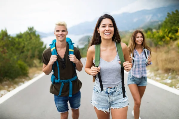 Hiking with friends is so fun. Group of young people with backpacks walking together by the road