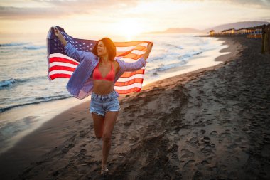 Mutlu kadın gülümseyip plajda koşarken bağımsızlık gününü kutluyor ve Amerika 'da özgürlüğün tadını çıkarıyor.