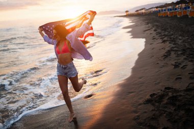 Mutlu kadın gülümseyip plajda koşarken bağımsızlık gününü kutluyor ve Amerika 'da özgürlüğün tadını çıkarıyor.