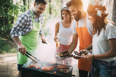 Açık havada barbekü akşam yemeği bira içme ve yemek yeme mutlu arkadaş grubu