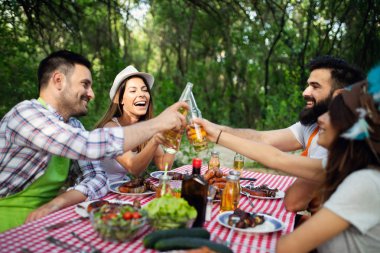 Barbekü yapma ve doğada yemeğe mutlu arkadaşlar