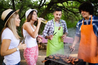 Açık havada barbekü akşam yemeği bira içme ve yemek yeme mutlu arkadaş grubu