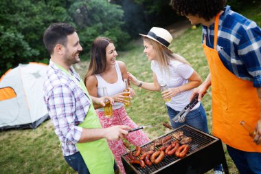 Barbekü yapma ve doğada yemeğe mutlu arkadaşlar
