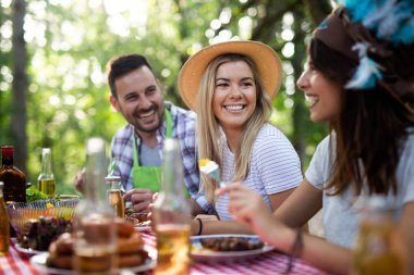 Açık havada barbekü akşam yemeği bira içme ve yemek yeme mutlu arkadaş grubu