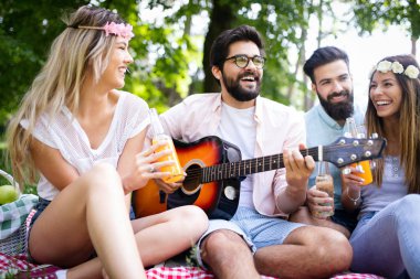 Mutlu genç arkadaşlar parkta piknik yapıyor. İnsanlar ,eğlenmek, gülümseyen, gitar kavramı çalmak
