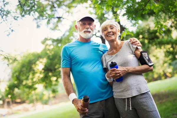 Fitness, sport and lifestyle concept - happy senior couple in sports clothes outdoors