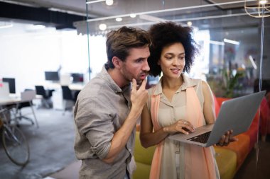 Ofiste iş arkadaşlarıyla birlikte çalışan ve iletişim kuran bir grup iş adamı.