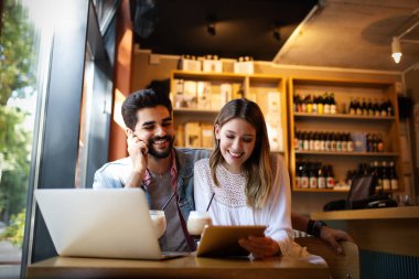 Genç mutlu çift laptop ve gülümseyen kafede çalışıyor.