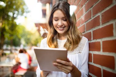 Mutlu gülümseyen kız online çalışan veya okuyor ve tablet kullanırken öğrenme