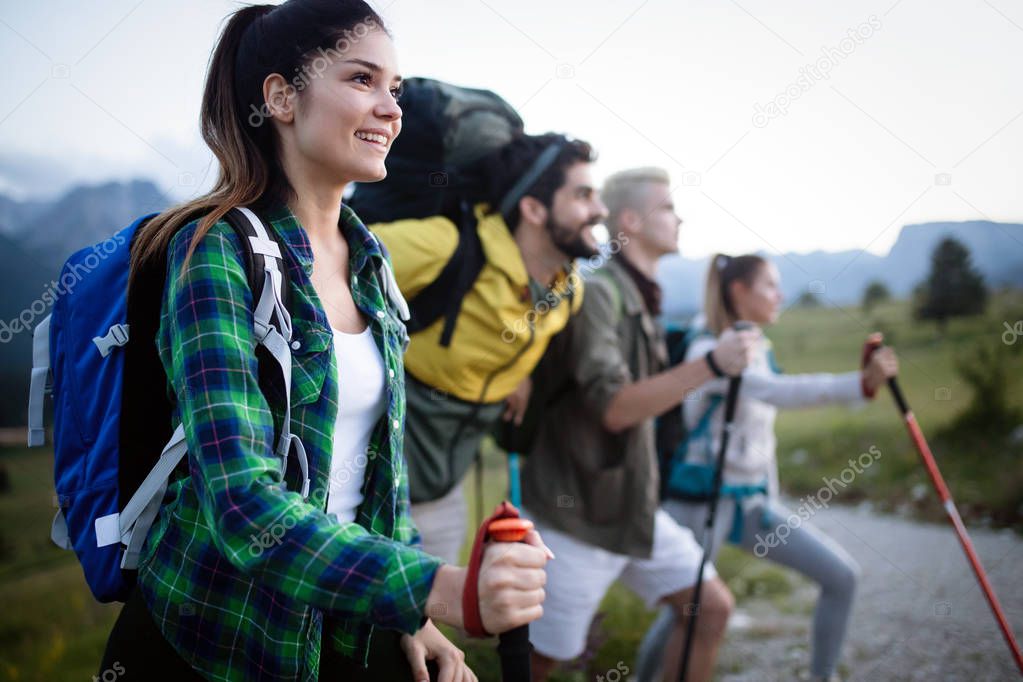 Group of hikers with backpacks and sticks walking on mountain