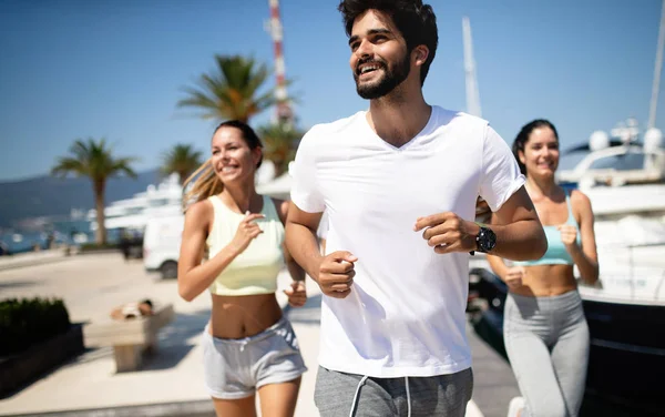 Happy fit people running and jogging together in summer sunny