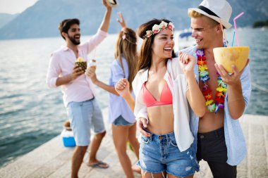 Bir grup arkadaş sahilde eğleniyor ve kokteyl içiyor.