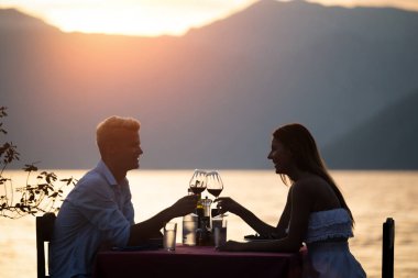 Genç çift sahilde romantik gün batımı akşam yemeği paylaşımı