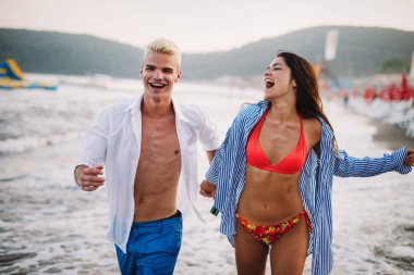 Mutlu mutlu çift gün batımında tropik bir plajda eğleniyor. Romantik tatil kavramı