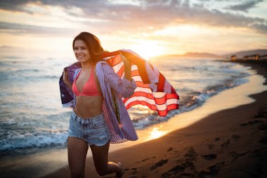 Mutlu kadın gülümseyip plajda koşarken bağımsızlık gününü kutluyor ve Amerika 'da özgürlüğün tadını çıkarıyor.