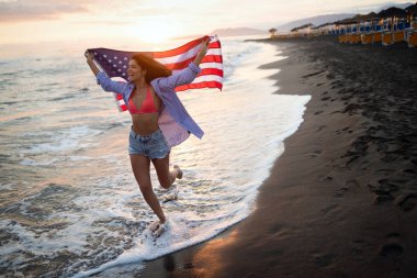 Mutlu kadın gülümseyip plajda koşarken bağımsızlık gününü kutluyor ve Amerika 'da özgürlüğün tadını çıkarıyor.