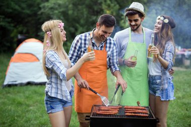 Doğada açık havada birlikte barbekü yapan bir grup arkadaş