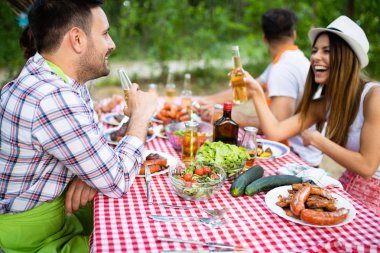 Barbekü yapma ve doğada yemeğe mutlu arkadaşlar