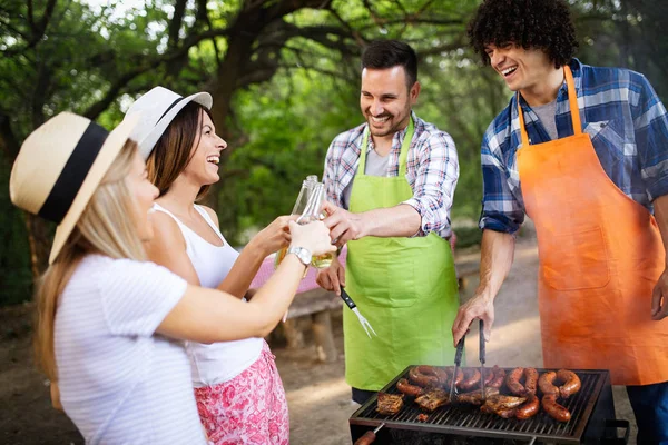 若い女性と男性のカップルは 友人と自然の中でバーベキューを焼きます — ストック写真