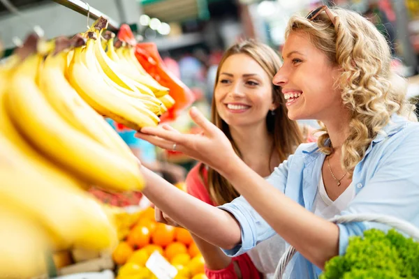 Young happy healthy women shopping vegetables and fruits on the market