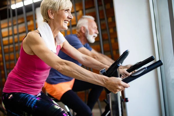 Senior fit couple exercising in gym to stay healthy