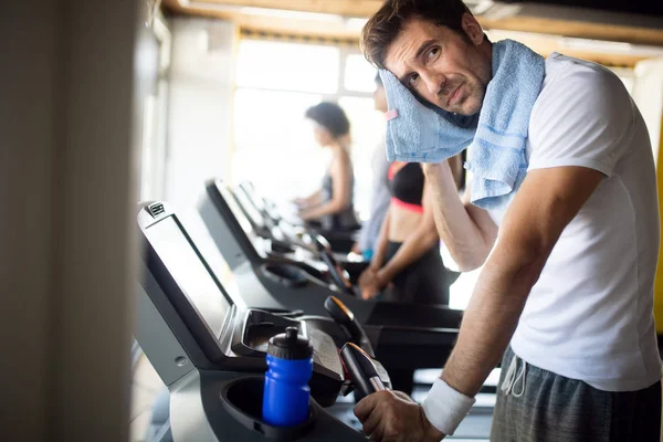 Handsome sporty man resting, having break after doing exercise in gym