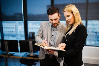 İş adamları ve iş kadını elindeki deftere bakıyor.