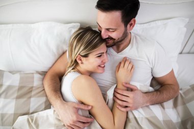 Güzel kadın ve çekici adam birlikte yatakta yatarken