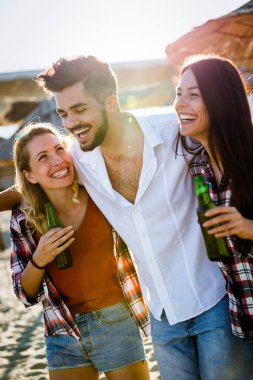 Gülüyor ve sahilde bira içme genç arkadaş grubu