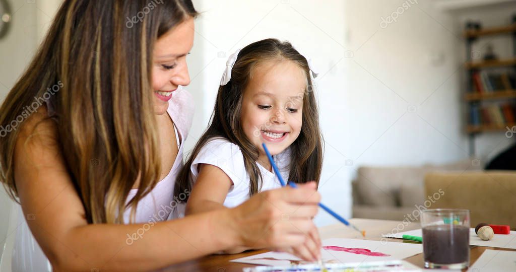 Mother looking how her child daughter drawing