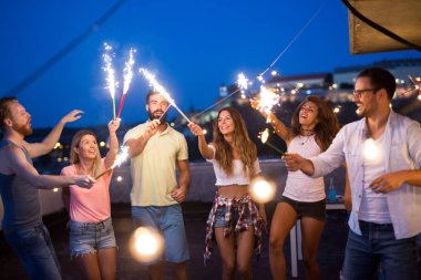 Bir çatı partisinde eğlenen, gitar çalan, şarkı söyleyen, dans eden ve sakinolan genç arkadaşlar