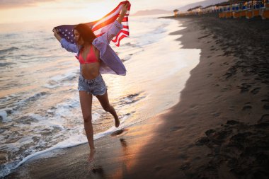 Mutlu kadın gülümseyip plajda koşarken bağımsızlık gününü kutluyor ve Amerika 'da özgürlüğün tadını çıkarıyor.