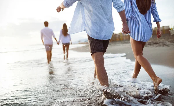 Group of friends having fun and walking on the beach at sunset — Stock Photo, Image