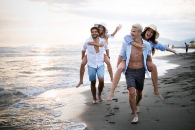 Gün batımı güneş ışığı altında sahilde eğlenen arkadaşlar.