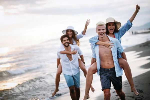 Teman bersenang-senang di pantai di bawah sinar matahari terbenam . — Stok Foto