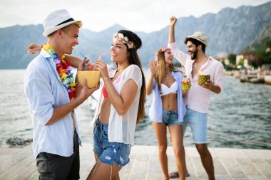 Bir grup arkadaş sahilde eğleniyor ve kokteyl içiyor.