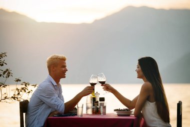 Tropikal tatil akşam yemeği sırasında tost genç romantik çift