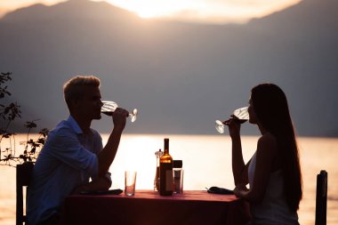 İnsanlar, kutlama, tatil, balayı ve romantizm konsepti. Genç çift sahilde romantik bir akşam yemeği yiyor..