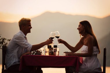 İnsanlar, kutlama, tatil, balayı ve romantizm konsepti. Genç çift sahilde romantik bir akşam yemeği yiyor..