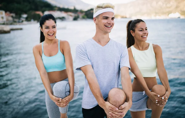 Fitness, sport, friendship and healthy lifestyle concept. Group of happy friends or sportsmen exercising and stretching outdoor