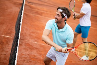 Tenis kortundaki yakışıklı genç adamın resmi. Tenis oynayan adam. Tenis topu atan adam. Arka plan olarak güzel orman alanı