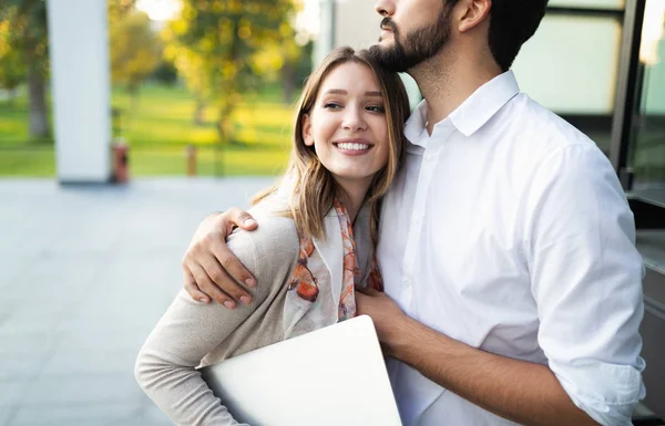 Mutlu genç çift dışarıda sarılıp gülüyor.